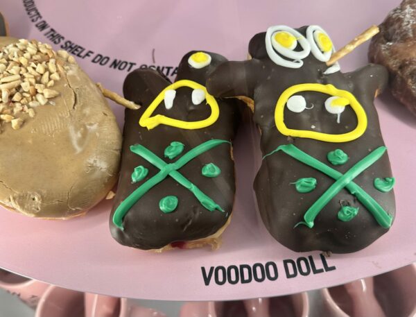 Voodoo Doughnuts infamous donuts shaped as little voodoo dolls. Chocolate covered with big yellow and green eyes, with a pretzel sticking out of them like a pin.