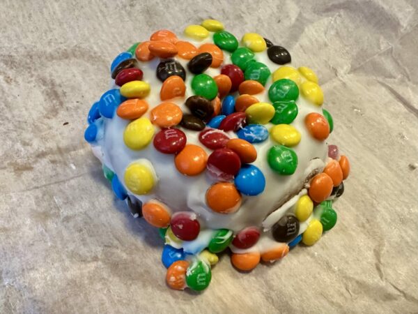 Donut with white glaze covered in M&Ms