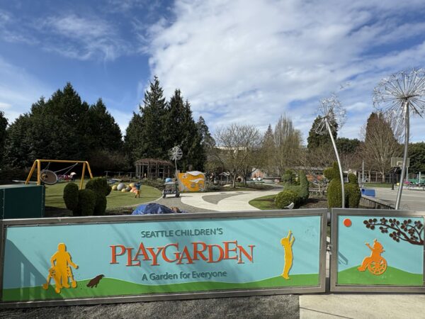 Large play structure in distance, behind sign that says PlayGarden