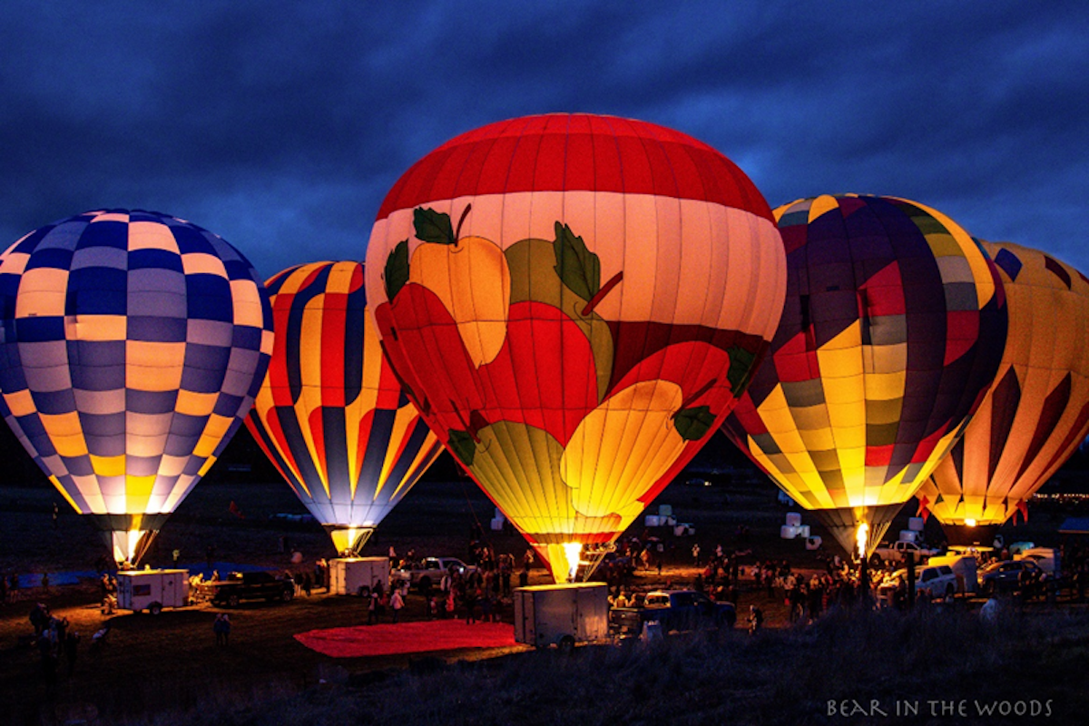 Four huge hot air balloons, glowing from lights within against a night sky