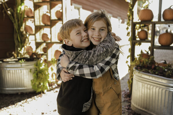 Two children hugging while surrounded by pumpkins at Craven Farm in Snohomish, Washington